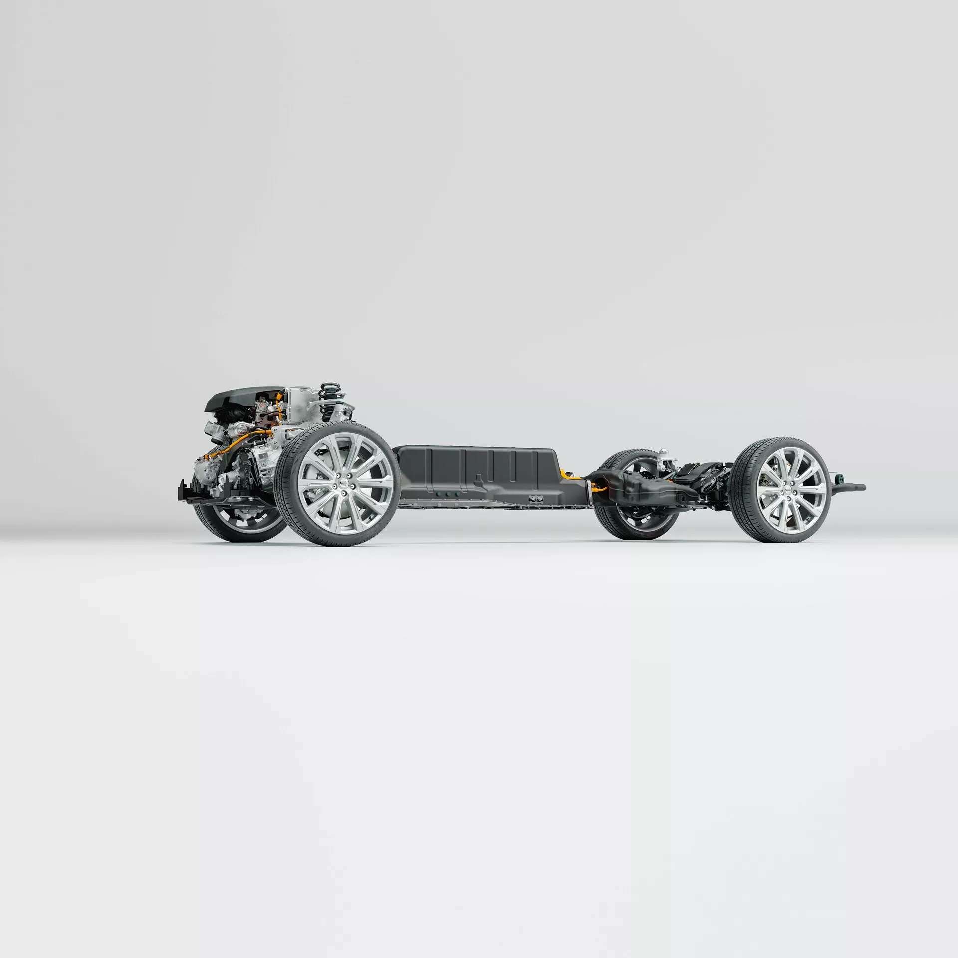 Vista laterale del telaio del Volvo XC60 2021 (seconda generazione-facelift). L'immagine mette in evidenza il telaio del veicolo, ruote con cerchi in lega moderni, componenti della sospensione, il gruppo propulsore anteriore e un pacco batteria centrale, tutto su uno sfondo neutro e pulito. La foto rivela dettagli intricati dell'ingegneria avanzata senza la carrozzeria o i componenti interni.