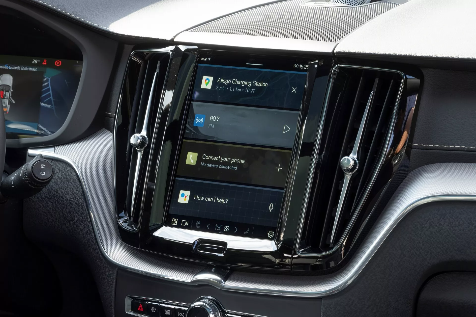 Vista interna di una Volvo XC60 2021 (seconda generazione-facelift) focalizzata sul sistema di infotainment centrale. Il display orientato verticalmente, simile a tablet e smartphone, è incorniciato da prese d'aria metalliche che suggeriscono un modello di fascia alta. Sotto lo schermo, i pulsanti fisici e una manopola rotante suggeriscono una combinazione di controlli touch e fisici. Il display di navigazione indica funzionalità GPS, con indicazioni per la connettività del telefono e il controllo vocale, suggerendo caratteristiche come Bluetooth, riconoscimento vocale e integrazione dello smartphone. L'ora è visualizzata alle 09:07. L'immagine mette in evidenza le caratteristiche del sistema di infotainment senza mostrare marchi o identificatori di modello.