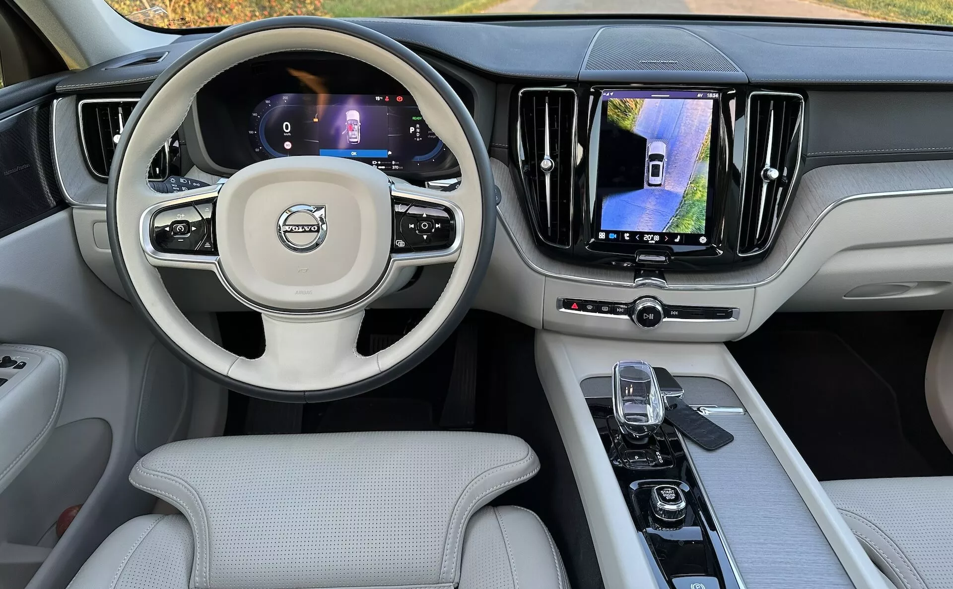 Vista interna della Volvo XC60 Recharge Plug-in Hybrid 2021 dal sedile posteriore, mostrando il cruscotto, display digitali, volante multifunzione e console centrale