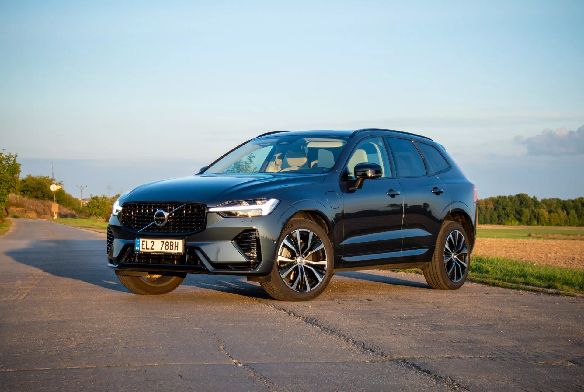 SUV di medie dimensioni Volvo XC60 Recharge Plug-In Hybrid del 2021 in un design elegante e sportivo, con fari LED Thor's Hammer, ruote in lega avanzate e griglia frontale scolpita, catturato in una luce pomeridiana calda da un angolo frontale di tre quarti che mostra il profilo laterale dinamico e la facciata anteriore.