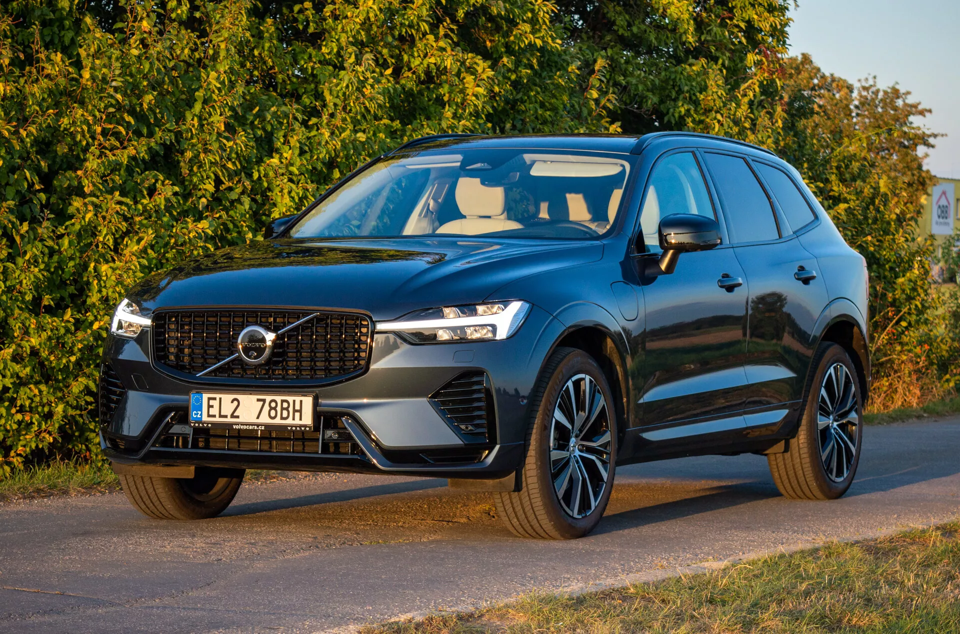 Volvo XC60 Recharge plug-in ibrido del 2021 di colore scuro, vista frontale a tre quarti che mostra fari LED, griglia emblematica, cerchi in lega sportivi e design aerodinamico, parcheggiata diagonalmente orientata verso sinistra con una vista dettagliata del frontale e del lato guidatore.