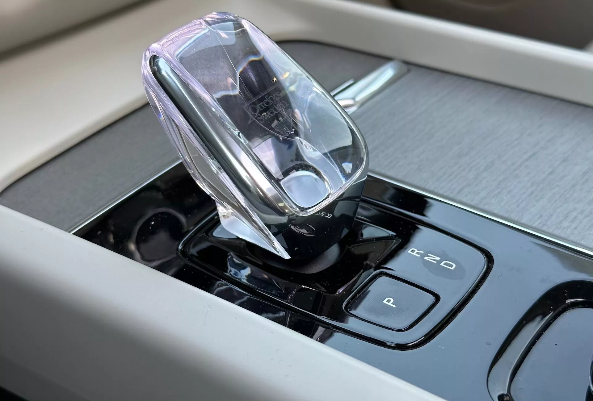 Vista ravvicinata dell'interno della Volvo XC60 Recharge Plug-in Hybrid 2021 con focus sulla leva del cambio elettronica di alta tecnologia e sui controlli touch-sensitive