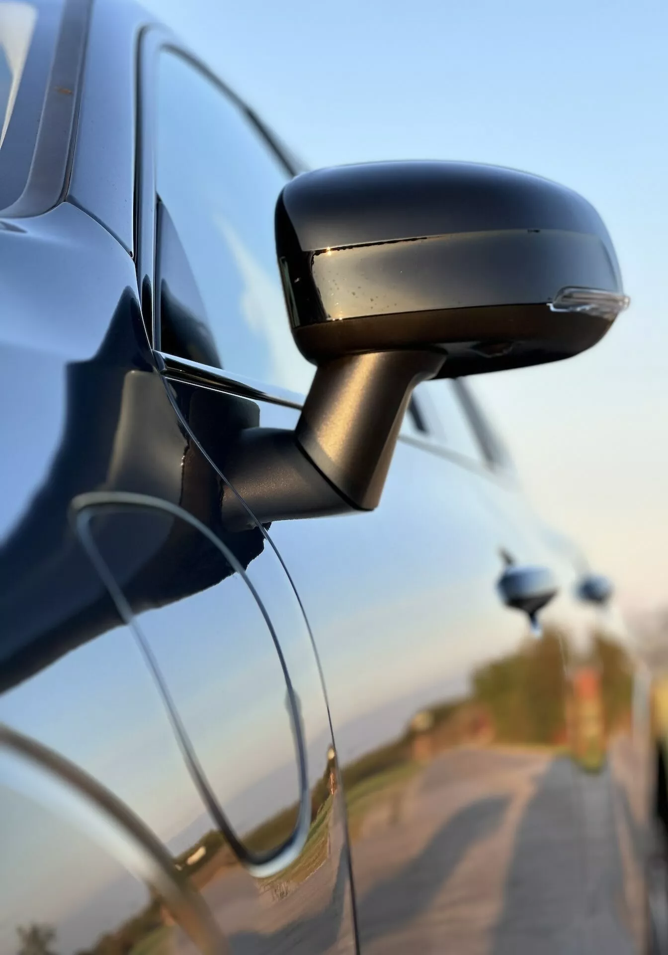 Vista ravvicinata dello specchietto laterale della Volvo XC60 Recharge Plug-In Hybrid 2021 che mostra il suo design elegante, l'indicatore di direzione integrato e l'attacco alla porta dell'auto, evidenziando la tecnologia automobilistica e le caratteristiche di sicurezza.