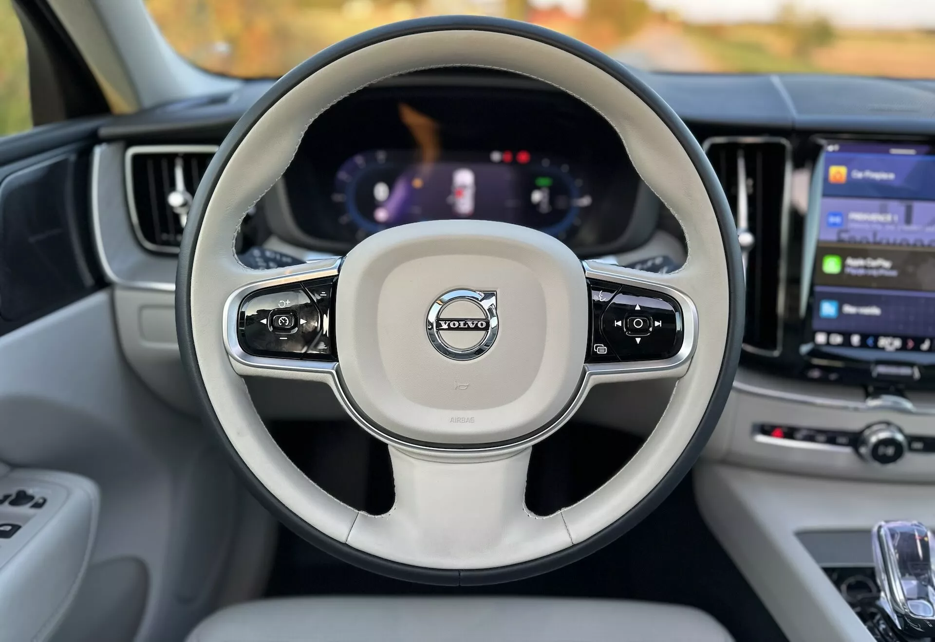 Vista interna di una Volvo XC60 Recharge Plug-In Hybrid 2021 dal sedile del conducente che mostra il volante con comandi montati, un cruscotto digitale e un grande sistema di infotainment touch screen