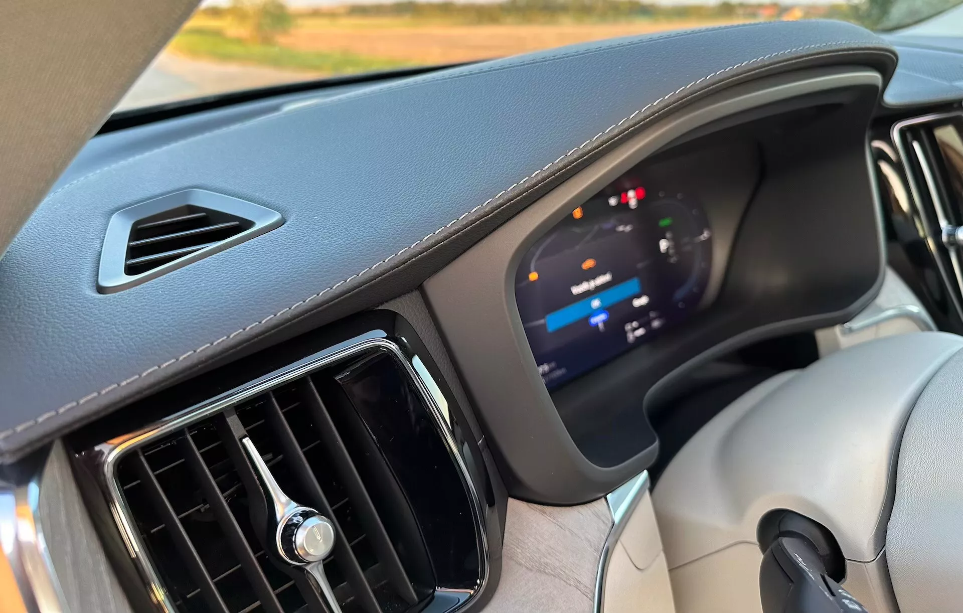 Vista interna di una Volvo XC60 Recharge Plug-In Hybrid 2021, che mette in mostra il cruscotto con un focus sul avanzato cluster strumentazione digitale e materiali di alta qualità, dalla prospettiva del sedile anteriore passeggero.