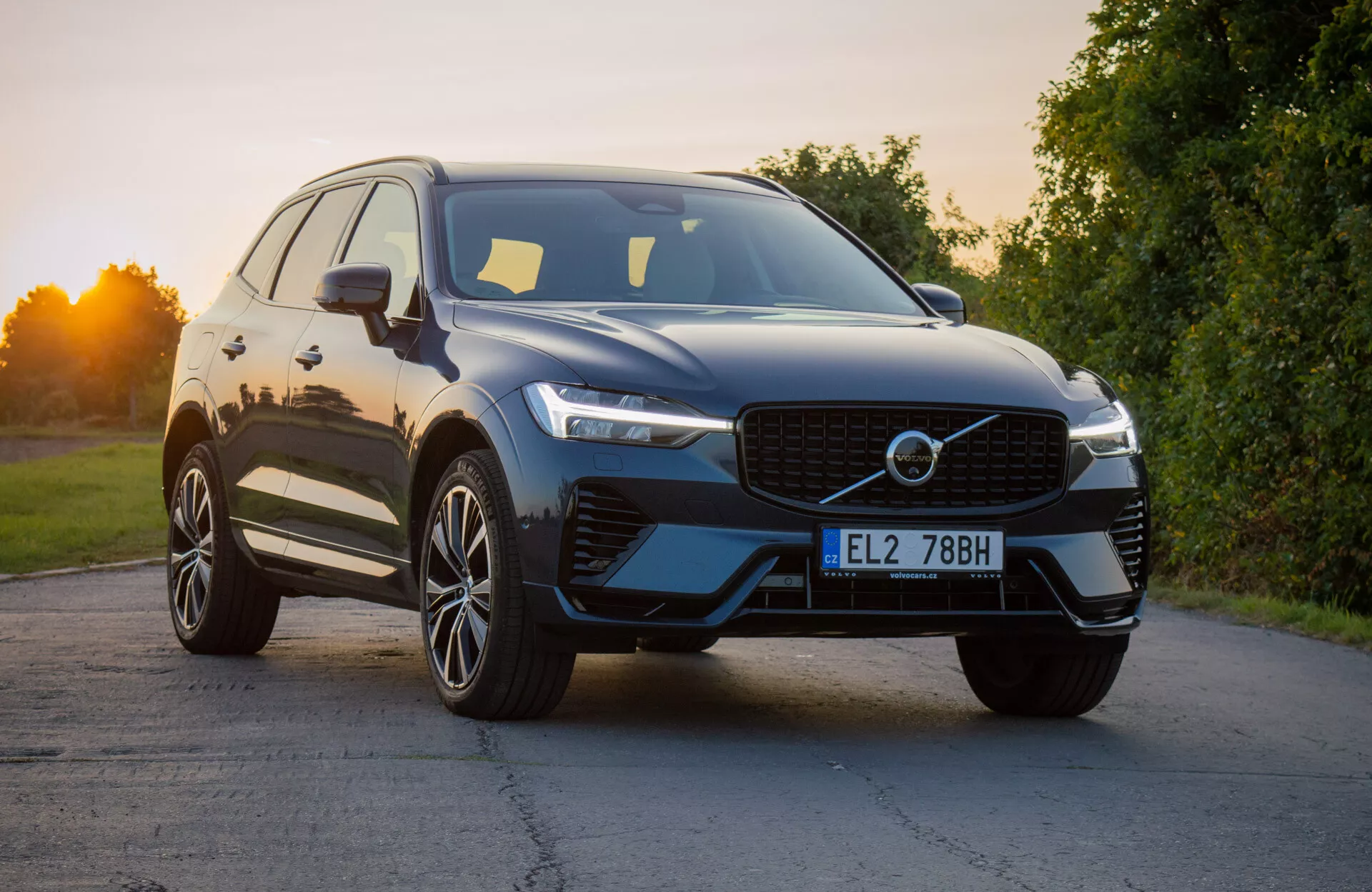 Volvo XC60 Recharge Plug-In Hybrid 2021 in un design moderno di SUV posizionato in leggera angolazione per evidenziare il quarto anteriore, mostrando la griglia distintiva, i fari a LED eleganti e il paraurti anteriore aerodinamico con prese d'aria integrate, completato da una finitura esterna lucida e ruote in lega a più razze sotto la luce naturale del giorno.