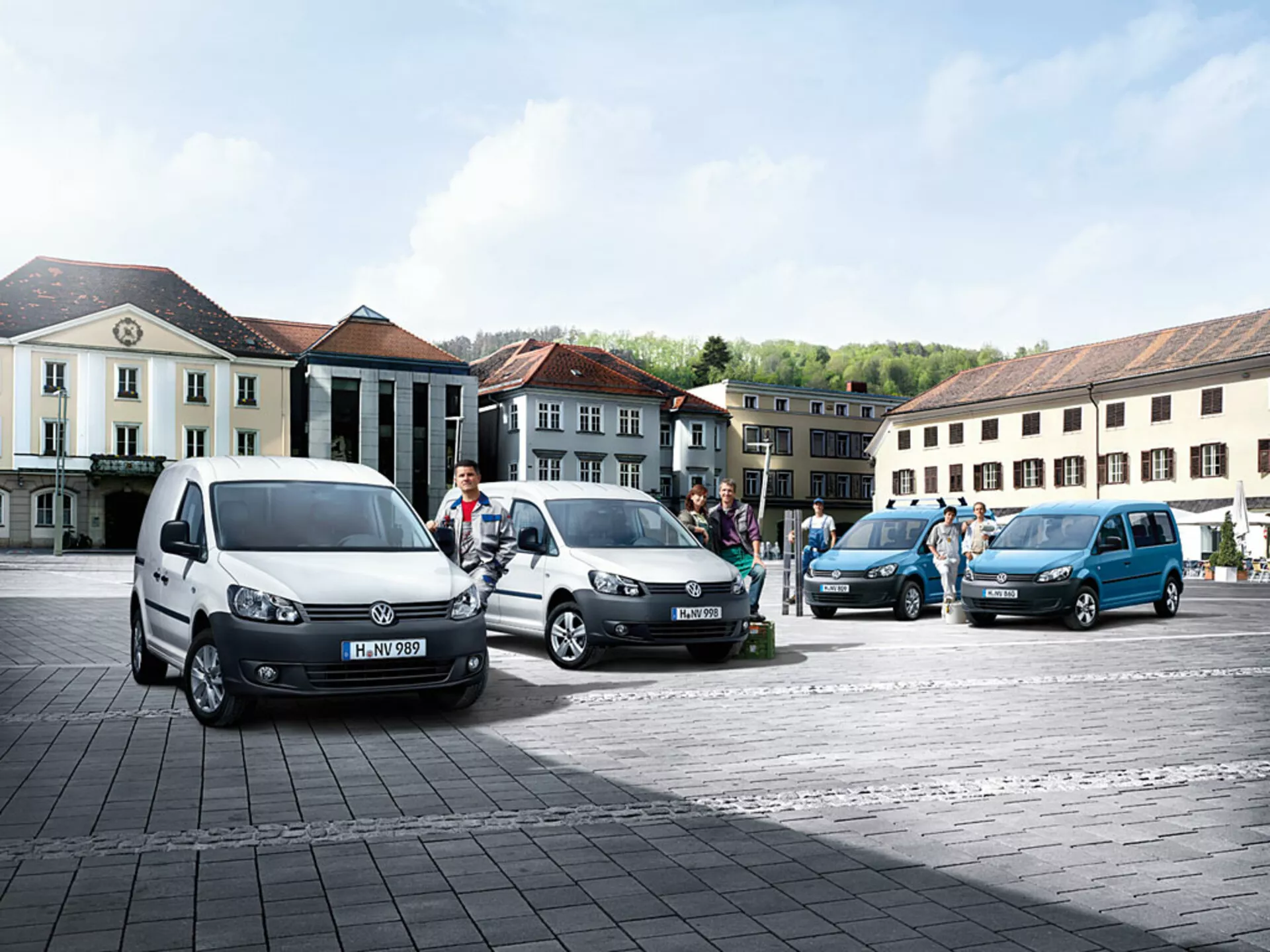 Furgoni polivalenti Volkswagen Caddy 2010 parcheggiati in linea diagonale su piazza in ciottoli, mostrando colori vari e angolazioni, con profili frontali e laterali distintivi visibili