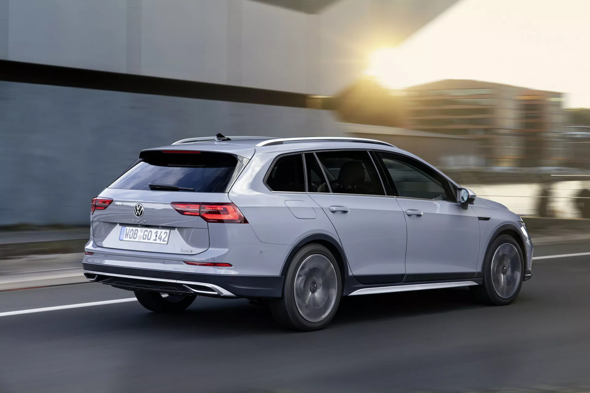 Station wagon Volkswagen Golf Alltrack 2017 in movimento, catturata in una visuale dinamica da tre quarti posteriore che mette in mostra la carrozzeria argento, luci posteriori LED, cerchi in lega e design aerodinamico su uno sfondo di strada sfocato.