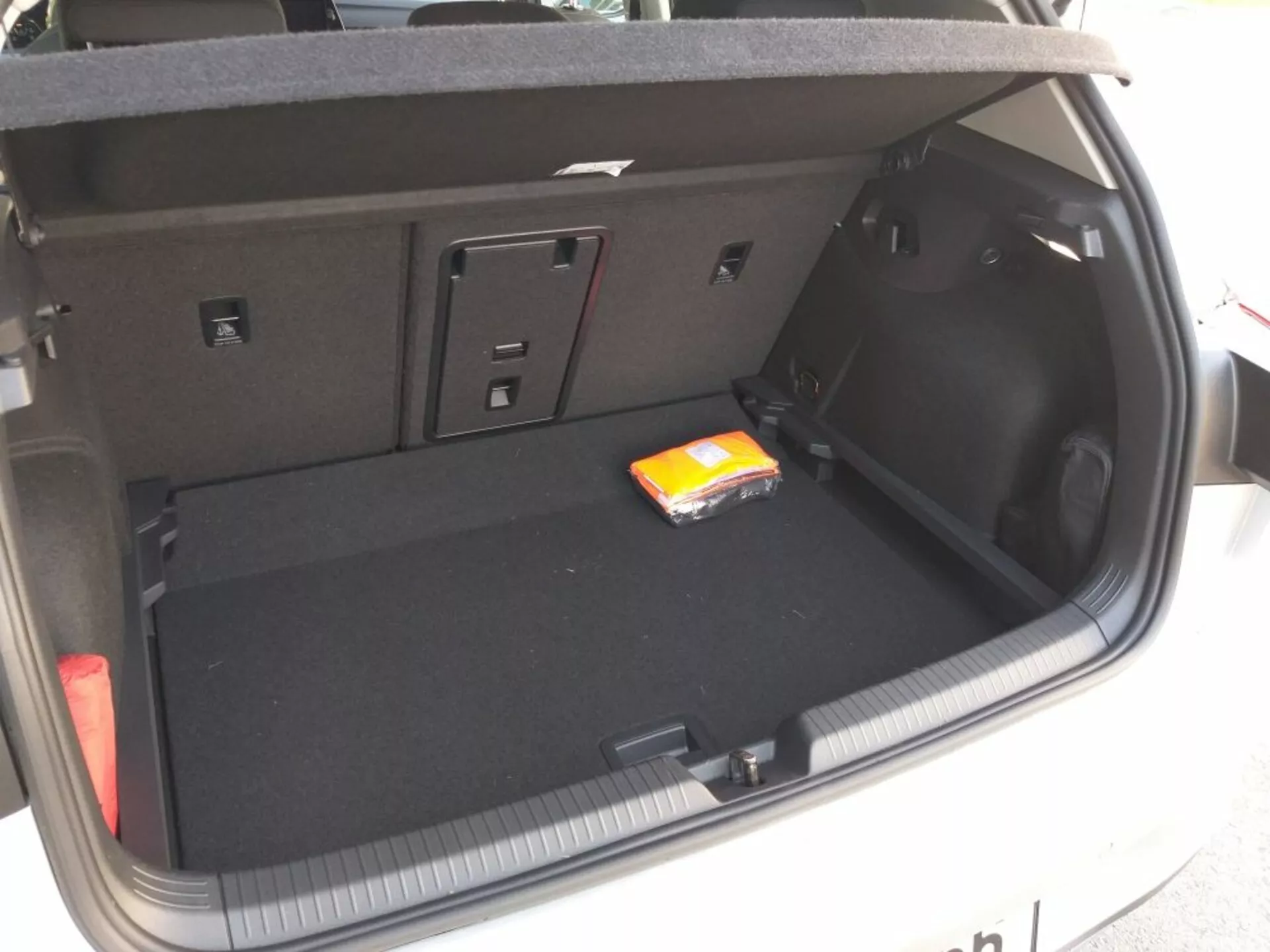 Compartimento bagagliaio del Volkswagen Golf GTD 2017 che mostra layout e design completi con rivestimento in moquette nera piatta, area principale di carico vuota con un piccolo pacco di salviette umide, vani laterali per piccoli oggetti o attrezzature, accesso ai sedili posteriori ribaltabili per spazio esteso, presa di corrente 12V sul lato destro, lampada integrata nel bagagliaio e dettagli che suggeriscono meccanismo di apertura/chiusura manuale