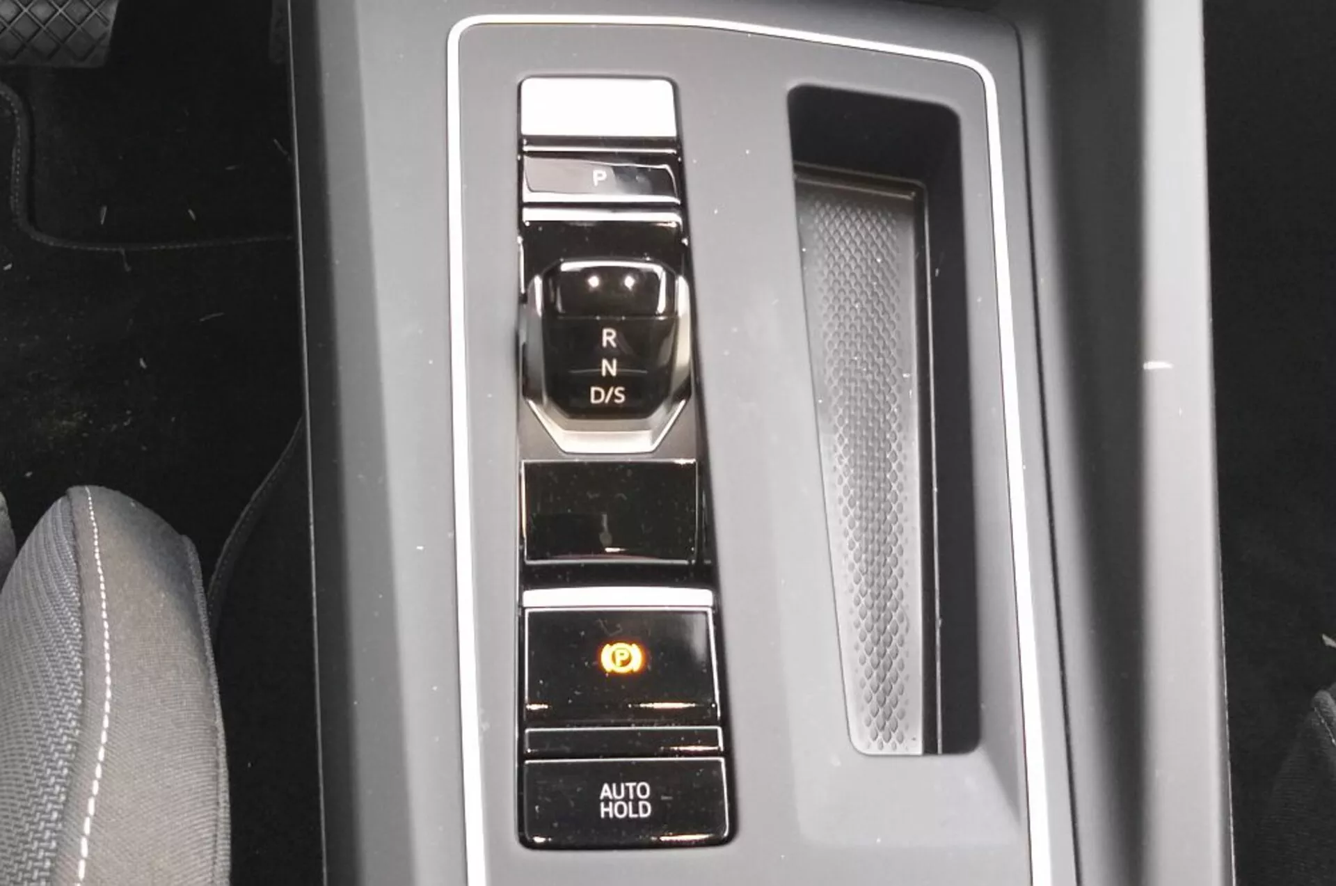 Vista ravvicinata del selettore di marcia elettronico del VW Golf GTD 2017 con disposizione dei pulsanti verticali su un pannello nero pianoforte con accenti cromati, mettendo in mostra la tecnologia moderna del sistema di trasmissione e funzionalità di comodità come il freno di parcheggio e la funzione AUTO HOLD